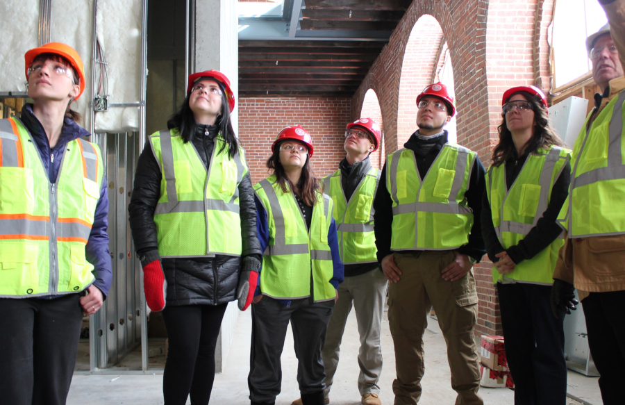 Students in hard hats and reflecting vests observing architecture