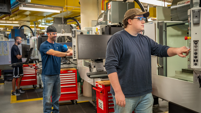 students standing working on CNC machines