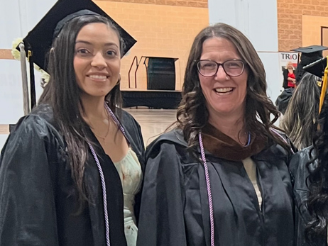alum Luisa Feeney and professor Jennifer Deforge at graduation in gowns