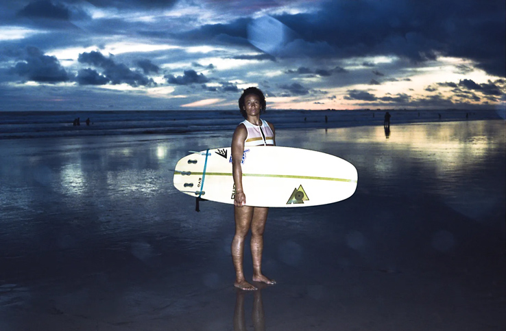 surfer posing board in hand at sunset