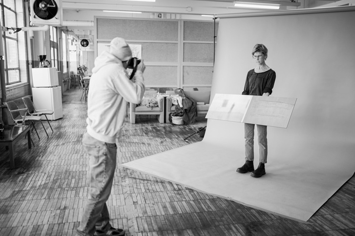 STCC student Ben Podmore photographs Nancy Diessner in the Fine Arts Program studio, holding a painting by her late husband, Daniel Feldman.