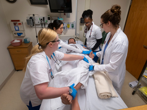 team of nursing students and professor holding simulation patient