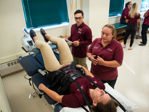 physical therapy students using chest straps and therapy table