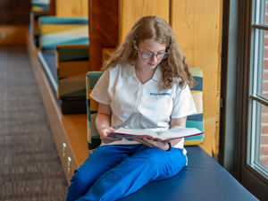 nursing student studying textbook in library