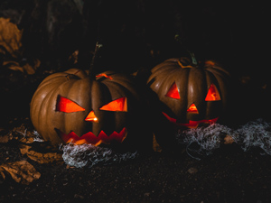 two jack-o-lanterns lit up in the dark