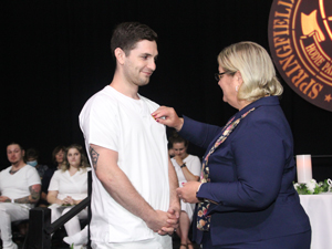 graduate in white scrubs getting pin on chest