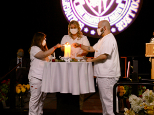 nursing graduates lighting candles on stage for pinning ceremony