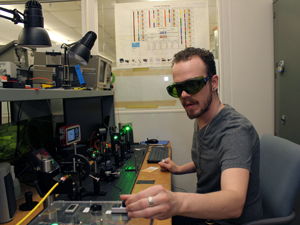 STEM student with goggles on operating lasers in optics and photonics lab