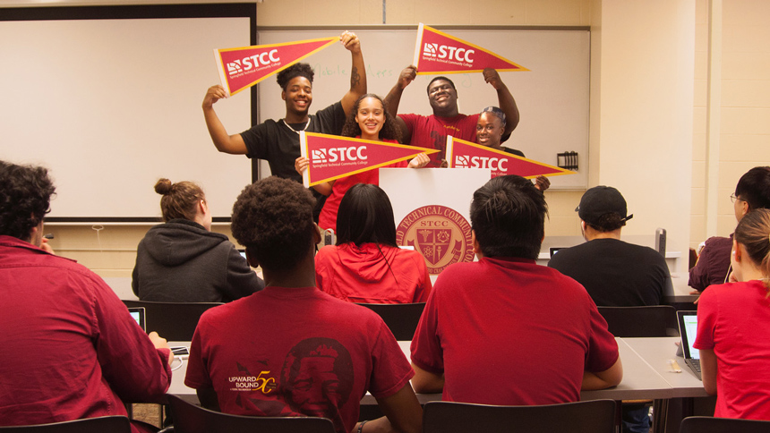 high school students holding STCC banners at front of classroom