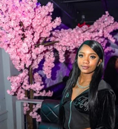 Demoney Rainford in front of pink cherry blossom tree