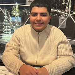 Joel Sanchez Kasza in sweater with light up white christmas trees in background