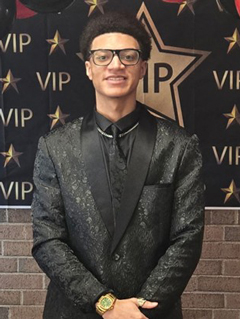 Zyhiem Clayton in a suit in front of VIP bulletin board