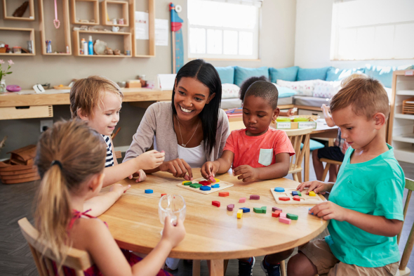 teacher with young children at a play table