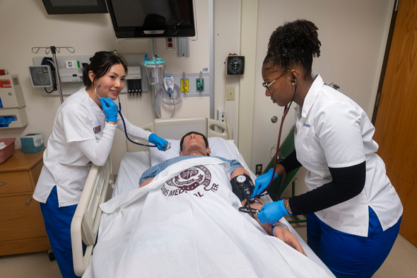 nursing students taking pulse of dummy in health simulation lab