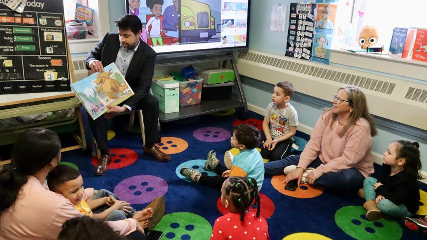 guest reading picture book to a classroom of children