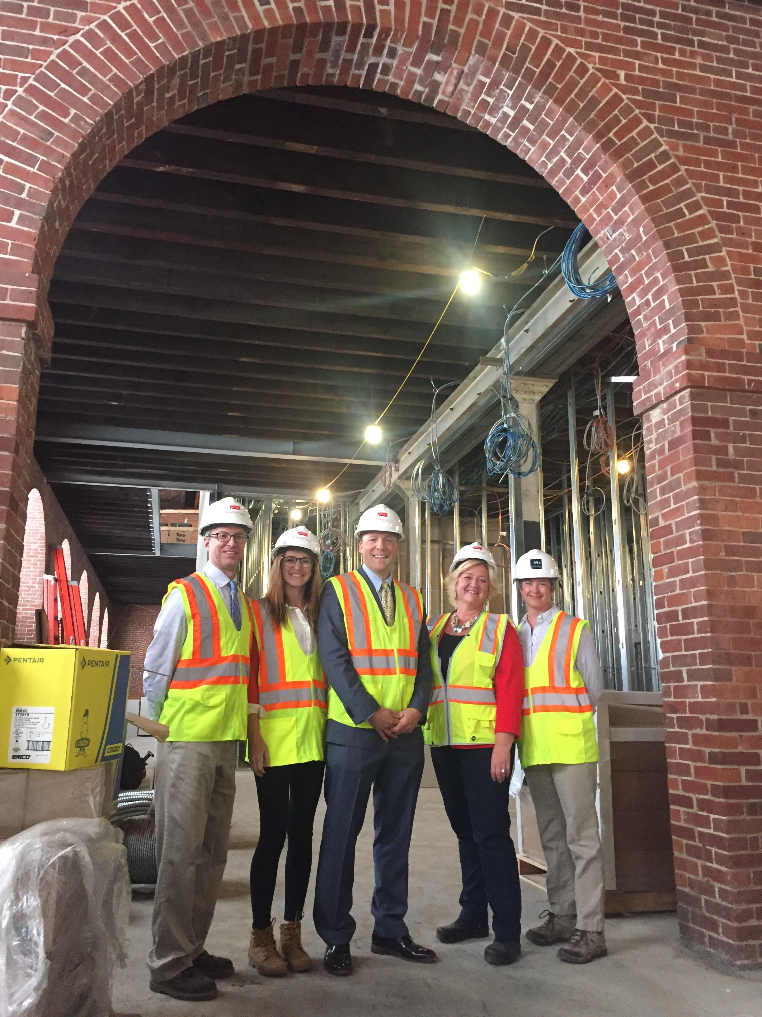 President Cook and others pose under an archway in Building 19