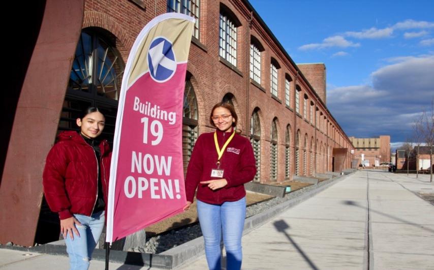 Students next to sign stating learning commons is open