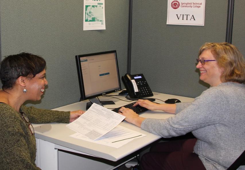 Janet Cummings, VITA site coordinator, and a professor sit down in a tax prep space.