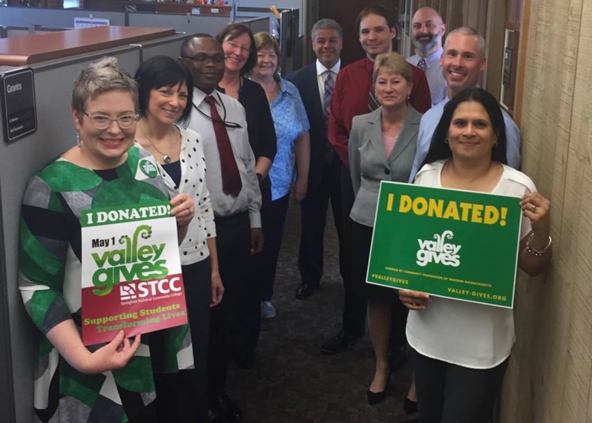 Staff from the business office hold signs stating they donated