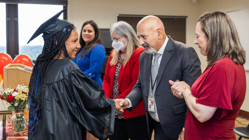 HiSET Graduate in cap and gown shaking hands