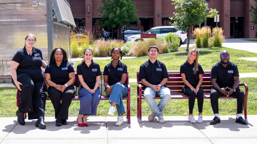 Student Ambassador group sitting on benches in front of the greenhouse gardens