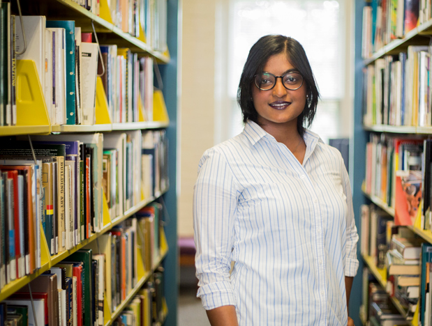 student in library between shelves of books