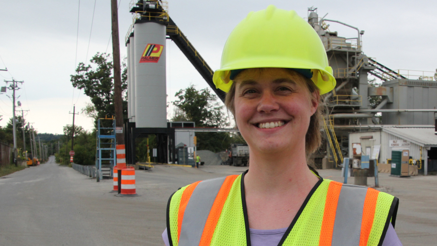 asphalt student with hard hat in front of paving equipment