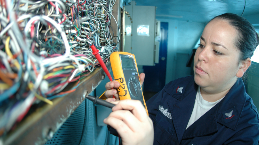electrician using multimeter and working with many wires