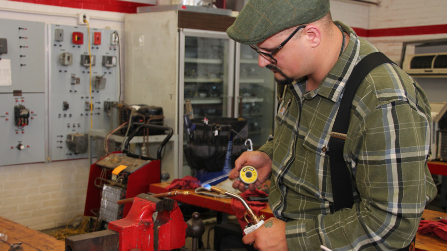 student soldering pipes in HVAC system